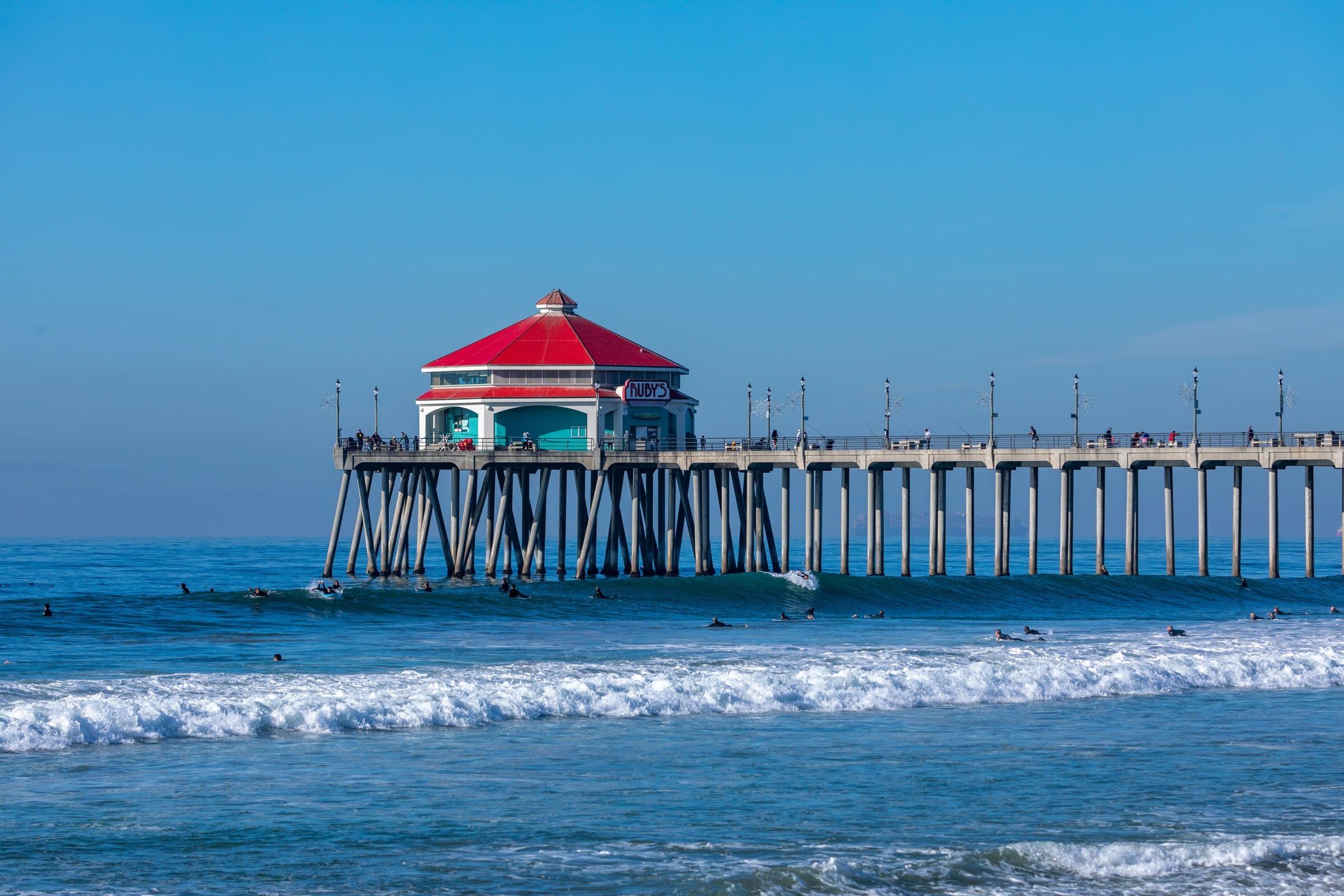 The Huntington Beach pier from the water, with surfers in the break