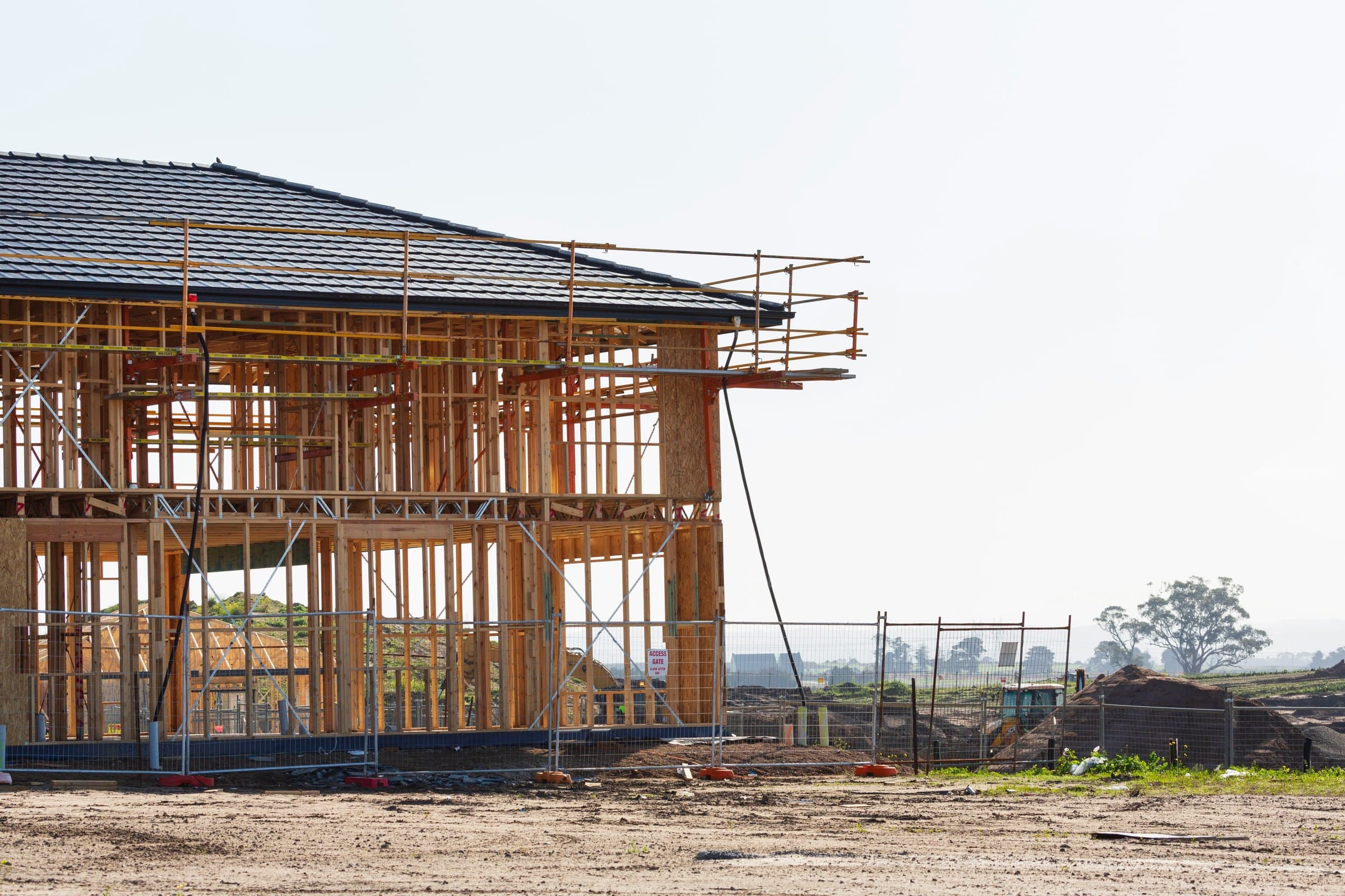 A house under construction, framed and roofed, with scaffolding still up