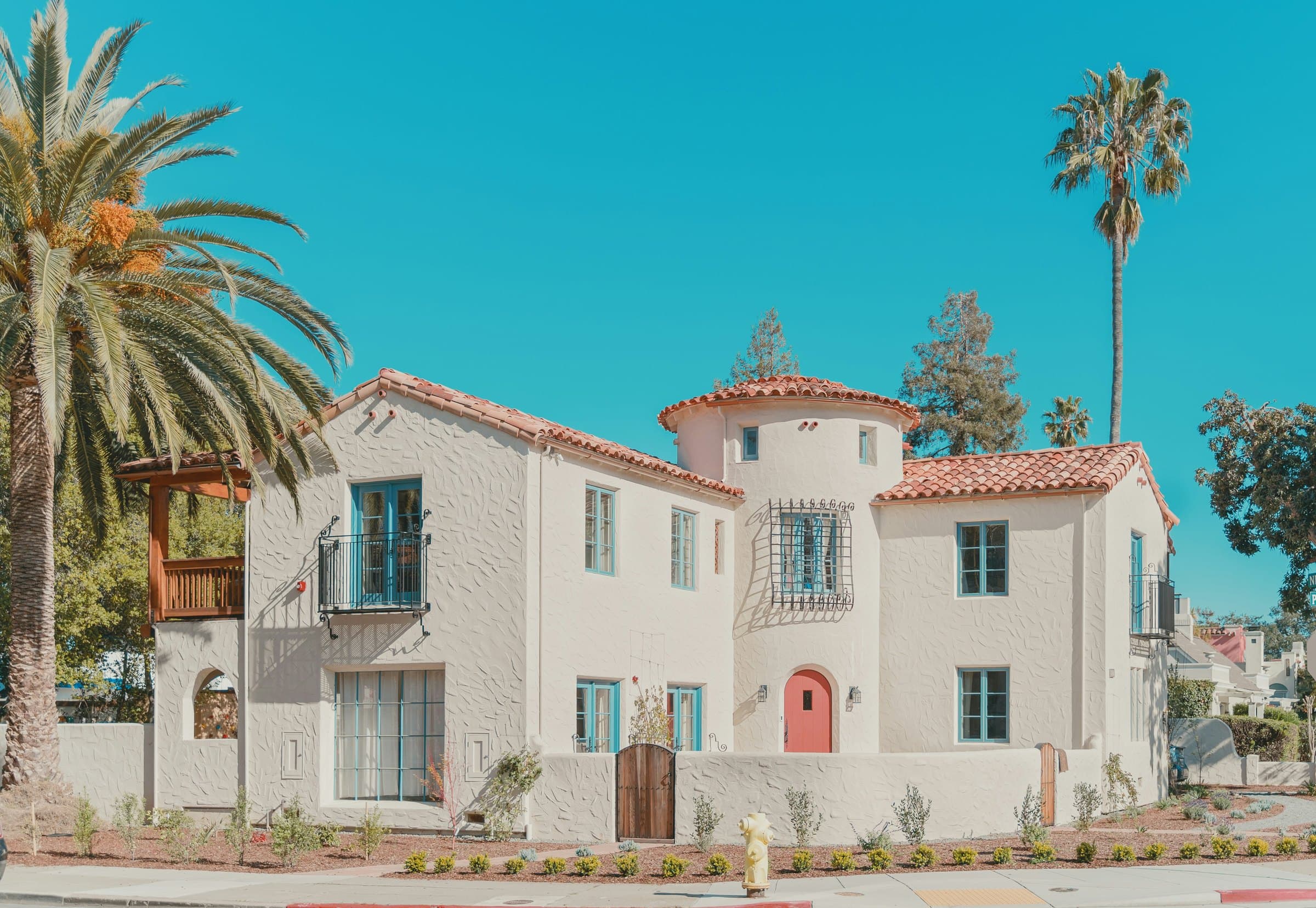 A small Spanish-revival apartment building under palm trees on a clear day